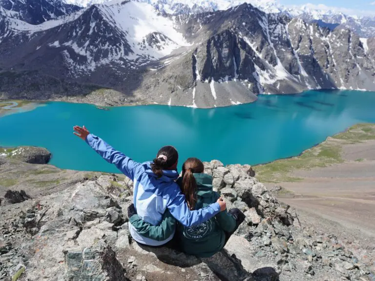 zwei Frauen mit Blick auf einen türkisfarbenen Bergsee in Kirgisistan