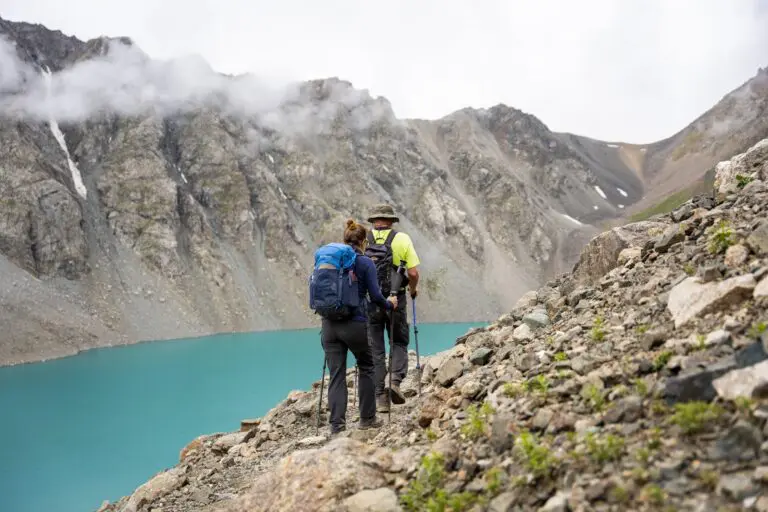 Two hikers with backpacks in front of Lake Ala-Kul in Kyrgyzstan