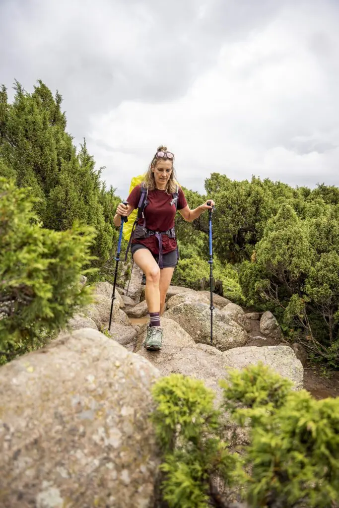 Hiker with trekking poles on a rocky trail in Kyrgyzstan