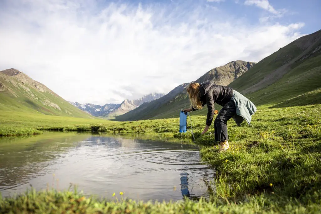Hiker filtering water from a mountain lake in Kyrgyzstan