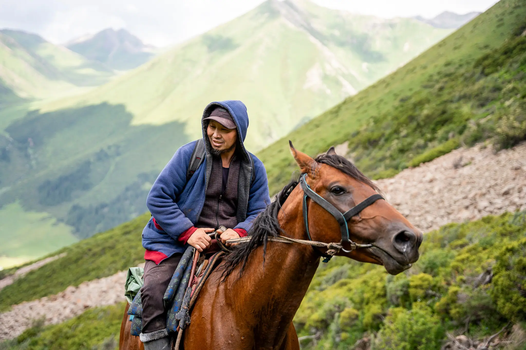 Man on horseback in the lush green mountains of Kyrgyzstan