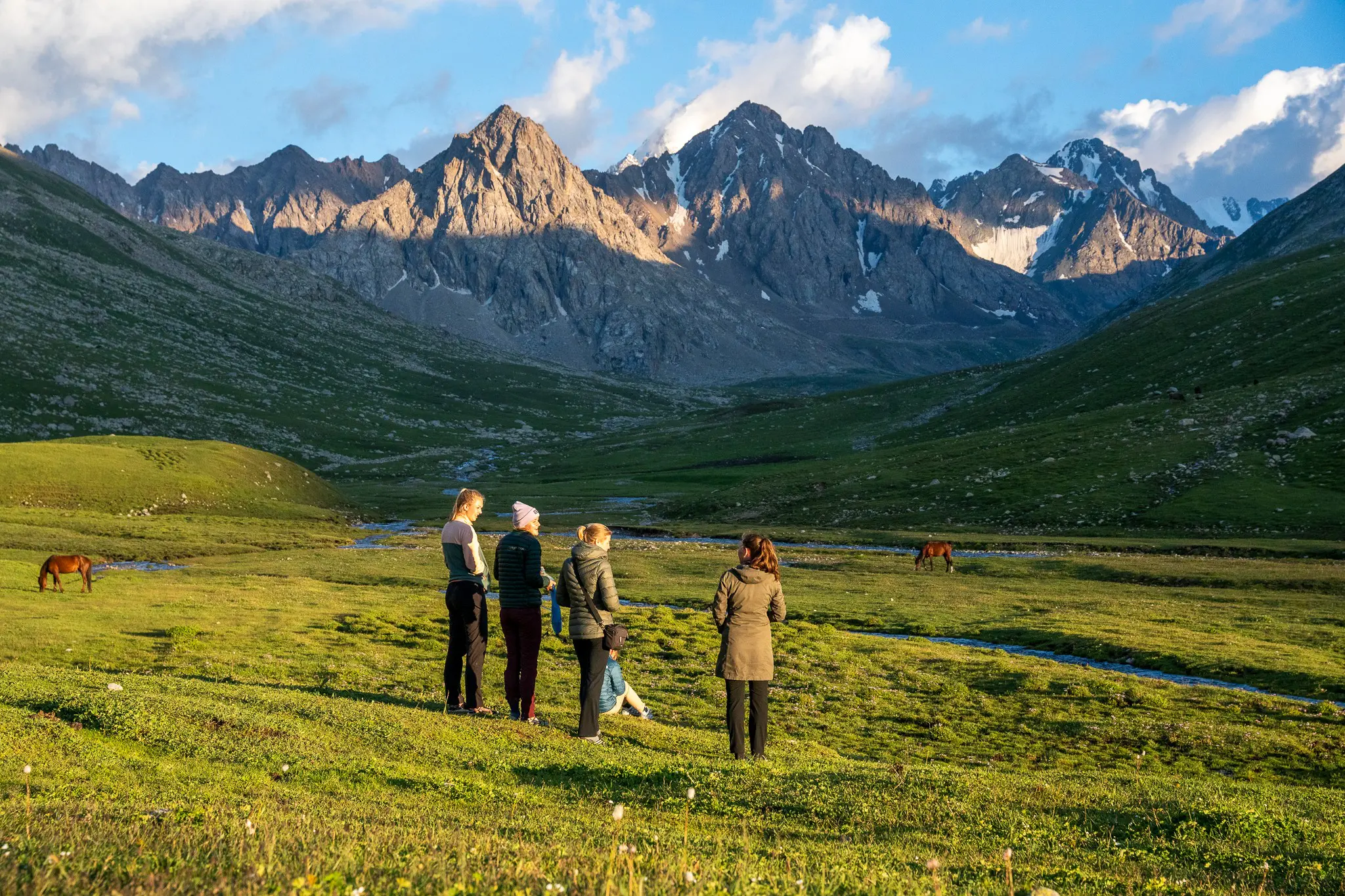Group of friends watching horses with the mountains of Kyrgyzstan in the background