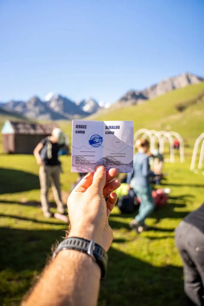 Person holding a campsite information sign in a mountain valley