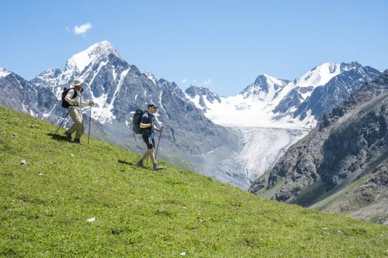 Two hikers with trekking poles on a slope in the Tian Shan