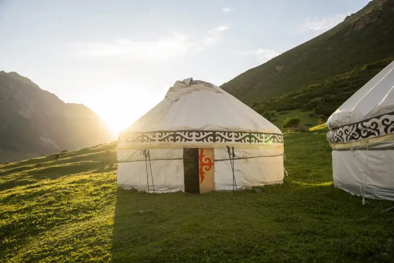 Traditional yurt camp in a mountain valley at sunset in Kyrgyzstan