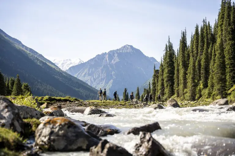 group of hikers by a river in a mountain valley